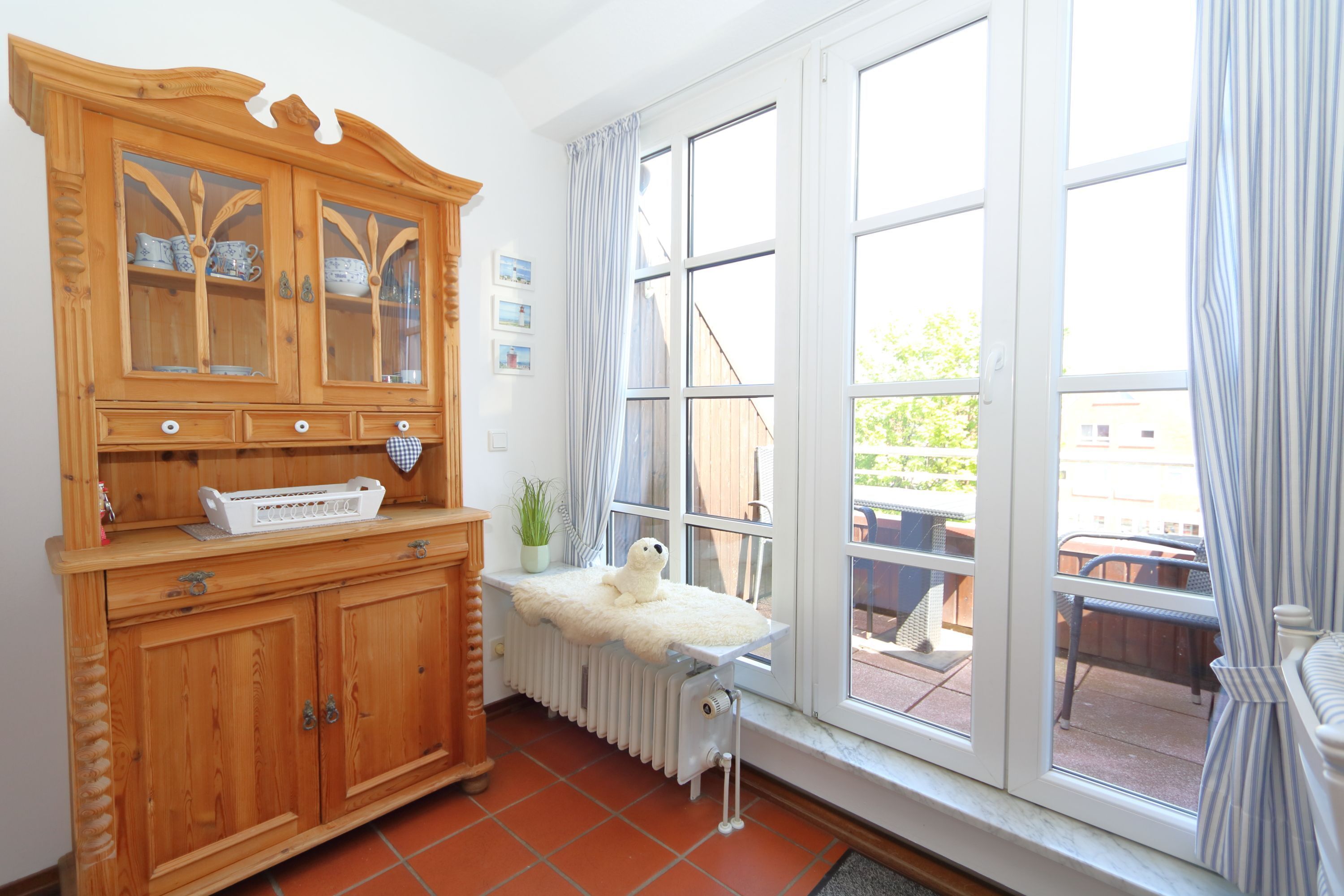 A room with a wooden cabinet, a radiator, and a large window with curtains.