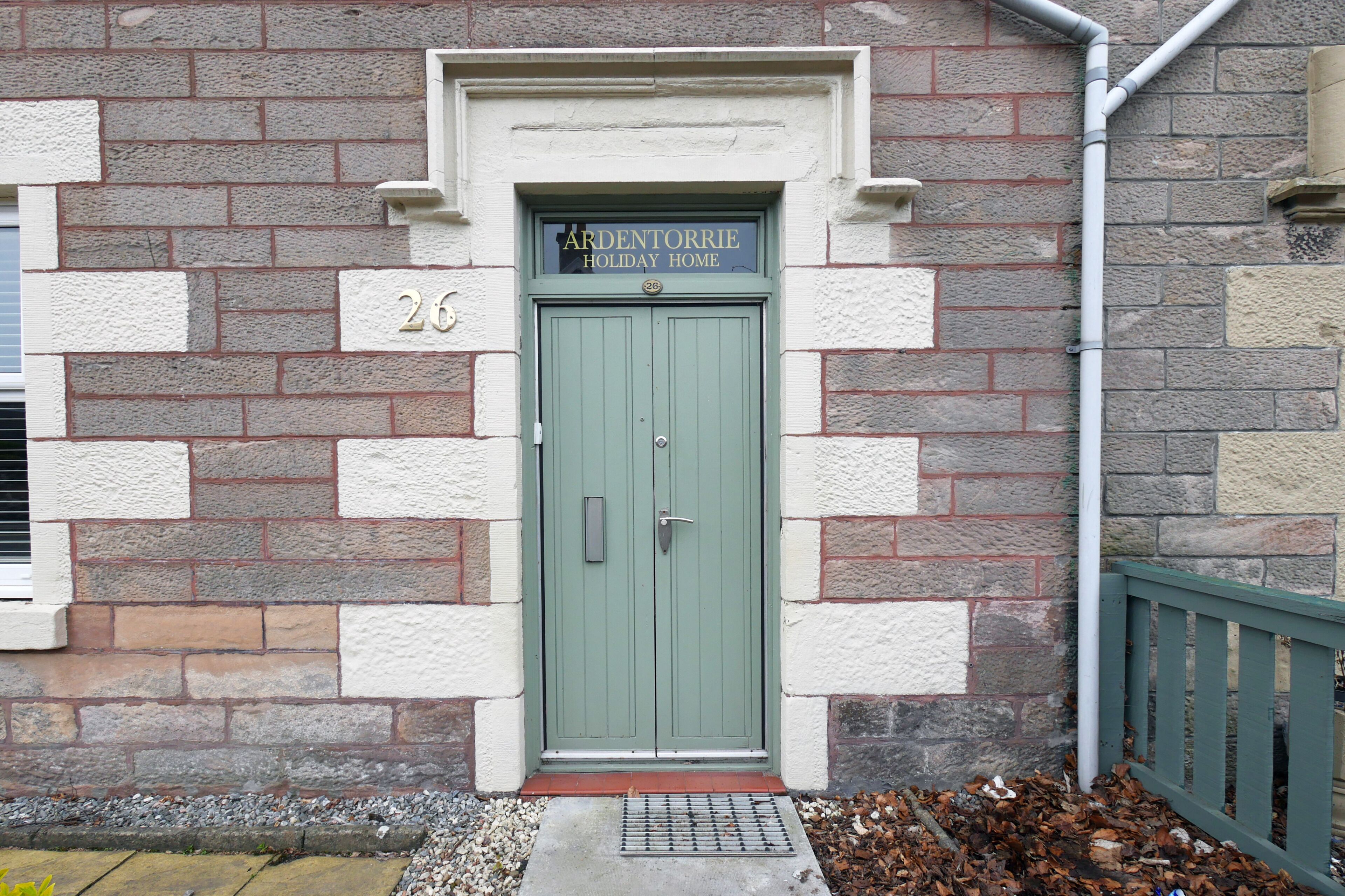 A green door with a sign above it reading "ARDENTORRIE HOLIDAY HOME."