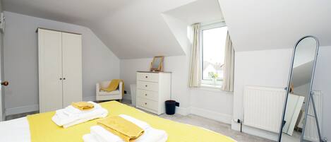 A bedroom with a bed, a dresser, a mirror, and a window.