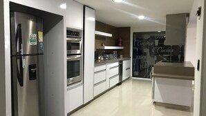 Eine moderne Küche mit Edelstahlgeräten, weißen Schränken und einer Glasrückwand.