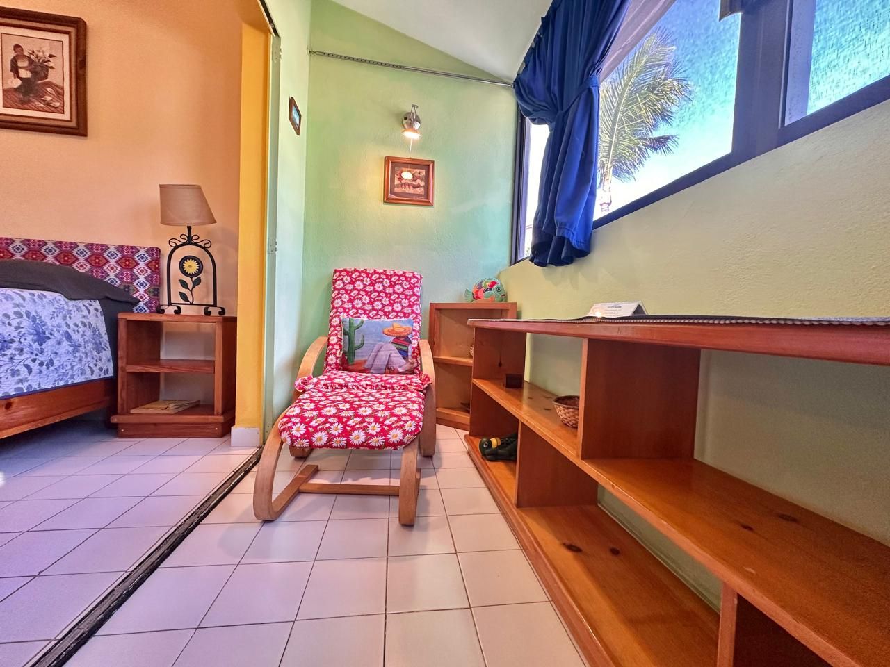 Une pièce comprenant un lit, un fauteuil à bascule, une petite table et une étagère.