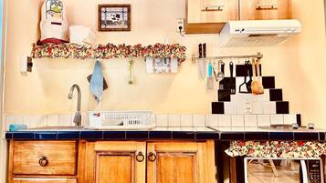 A kitchen with wooden cabinets, a microwave, a sink, and various kitchen utensils.