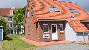A two-story brick building with a red-tiled roof, a satellite dish, and a sign that reads "moin".