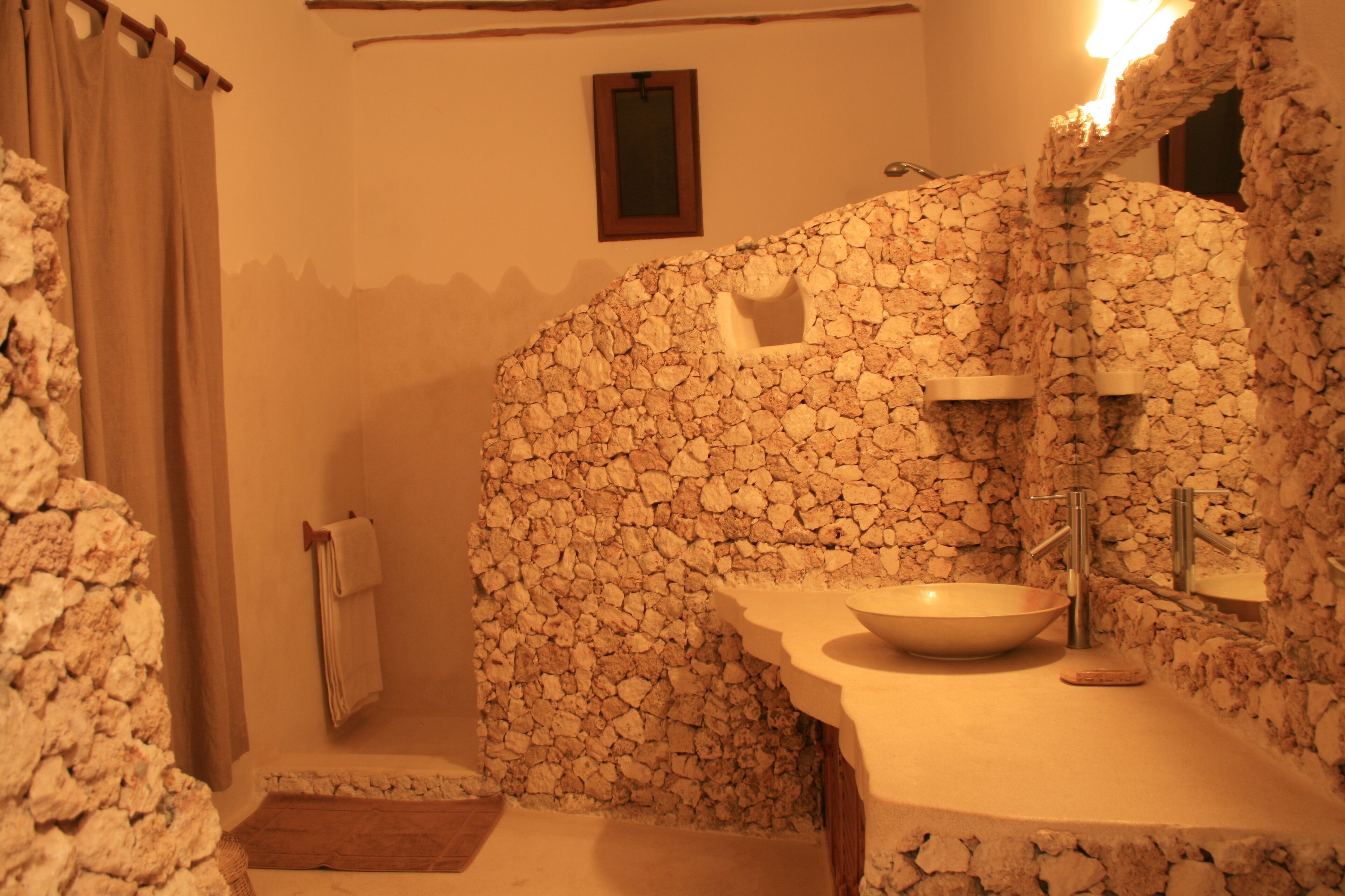 Ein Badezimmer mit Steinwand, Waschbecken und Spiegel.
