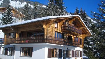 Perched among snow-covered trees, this chalet-style building offers a spacious balcony with a view.