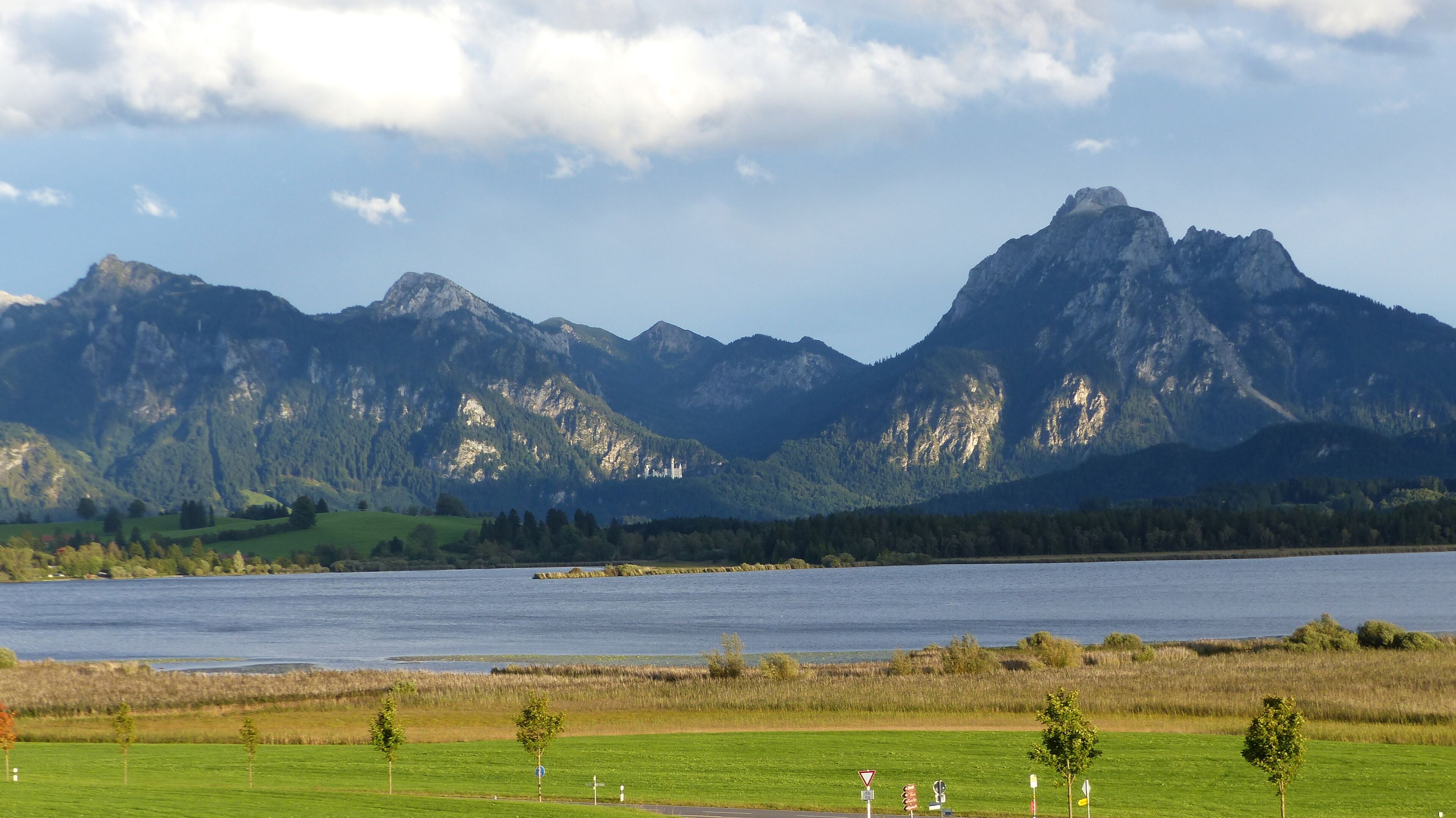 A mountain landscape with a lake and a castle on a hill.