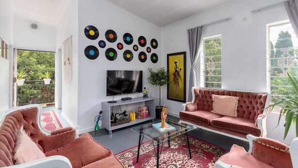 A living room with a sofa, a coffee table, a TV, and a wall decorated with vinyl records. - Stylish 2-bed Apartment in Centurion, Pretoria (Centurion)