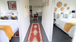A hotel room with two beds, a hallway with a red carpet, and a dining area with chairs and a table. - Stylish 2-bed Apartment in Centurion, Pretoria (Centurion)