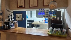 Uma bancada de cozinha com uma máquina de café, canecas e um letreiro de café.