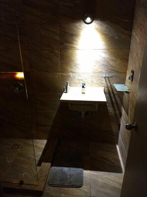 A bathroom with a sink, mirror, and a light fixture on the wall.