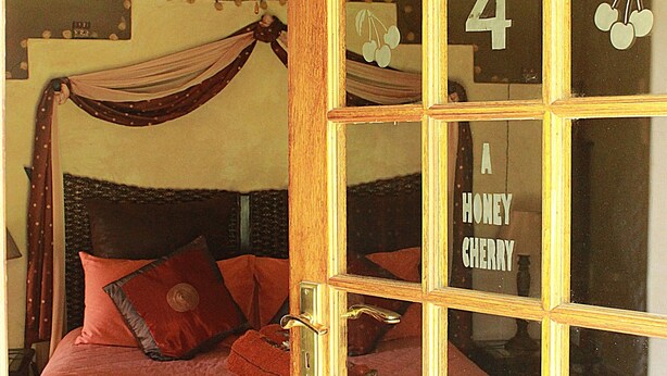 A room with a bed, a ceiling fan, and a door with a number and a fruit symbol. - Cherry Lane Self Catering and BB - Romantic Honeymoon Suite for 2 Bloemfontein (Bloemfontein)