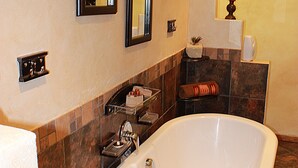 A bathroom with a freestanding bathtub, two wall-mounted mirrors, a towel rack, and a small shelf with toiletries. - Cherry Lane Self Catering and BB - Romantic Honeymoon Suite for 2 Bloemfontein (Bloemfontein)