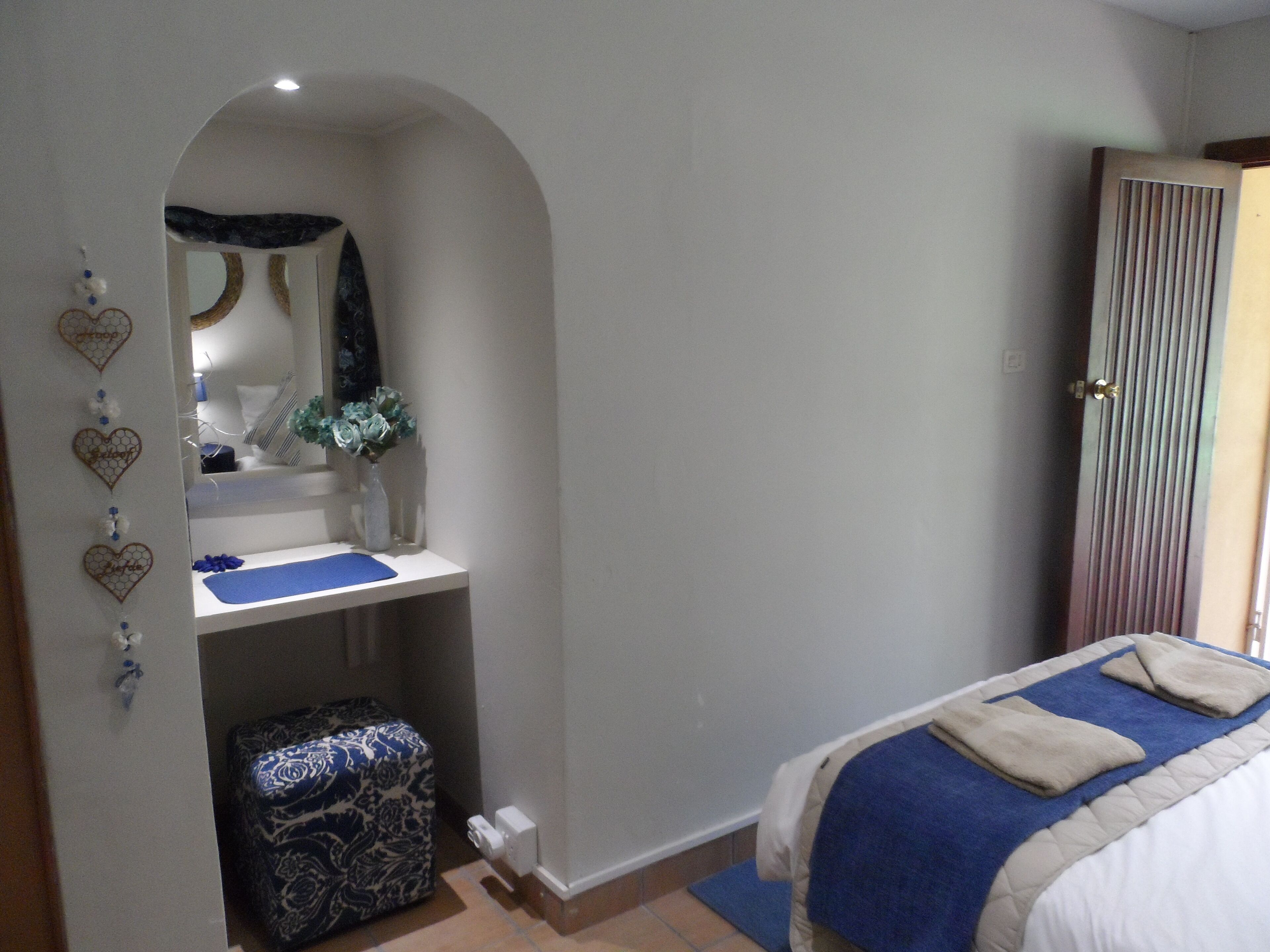 A bedroom with a bed, a vanity with a mirror, and a wardrobe.