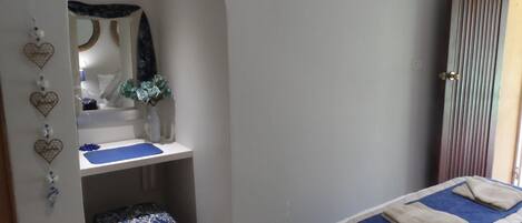 A bedroom with a bed, a vanity with a mirror, and a wardrobe.