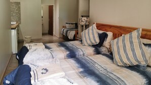 A hotel room with a large bed, a wooden headboard, and a bedside table with a lamp. - Cozy Triple Room With King Sized bed and Single Bed, Near Bloemfontein (Bloemfontein)