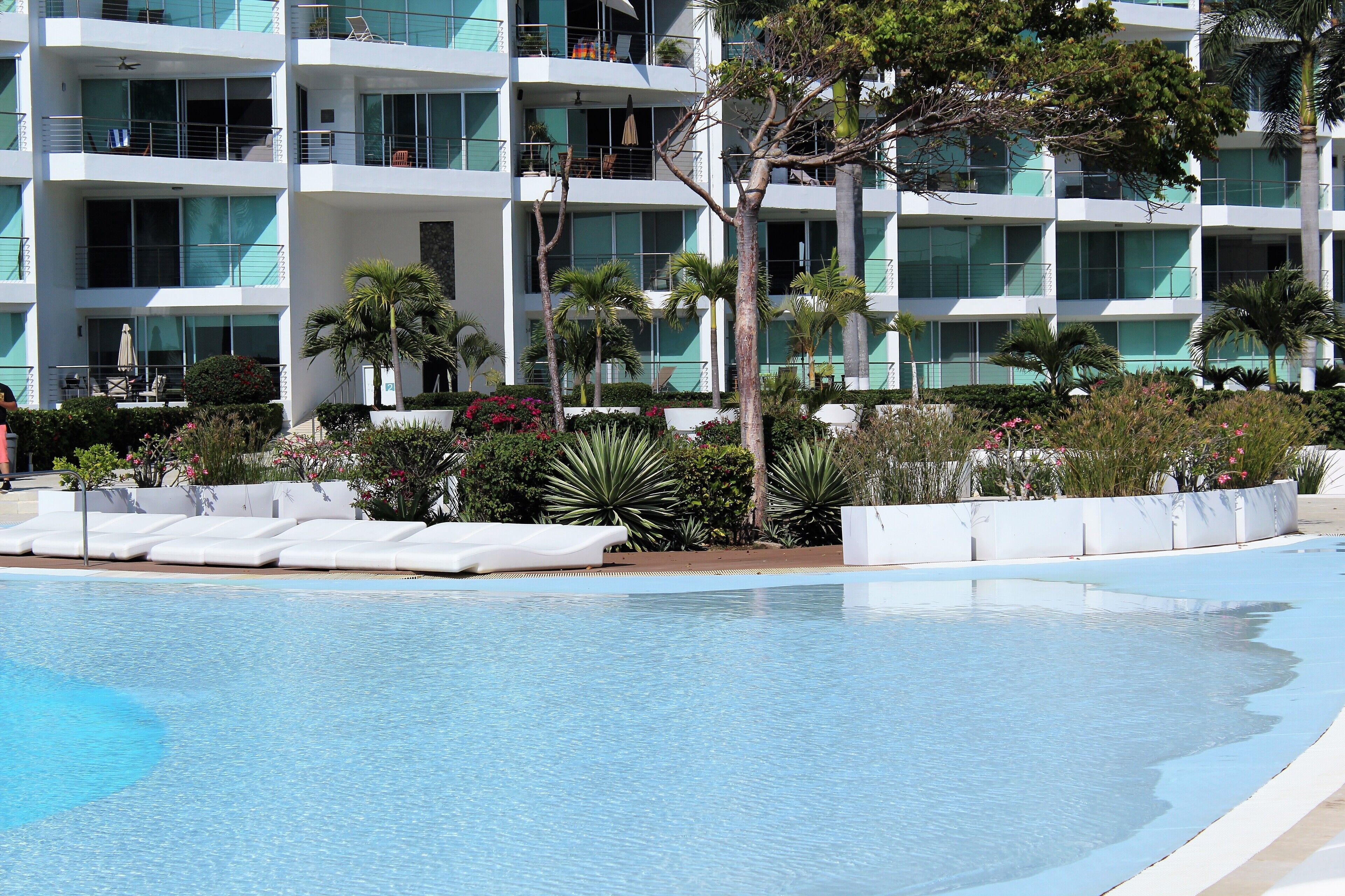 A hotel with a swimming pool, multiple balconies, and lush landscaping.