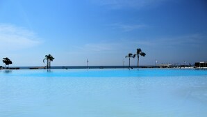 A large, clear swimming pool with palm trees and flags in the background. - Studio Ocean View in the Best Location of Vallarta (Nuevo Nayarit)