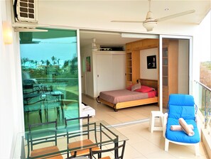 A room with a bed, a chair, a table, and a balcony with a glass door. - Studio Ocean View in the Best Location of Vallarta (Nuevo Nayarit)