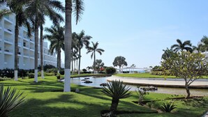 A hotel with a pool, palm trees, and a well-maintained lawn. - Studio Ocean View in the Best Location of Vallarta (Nuevo Nayarit)