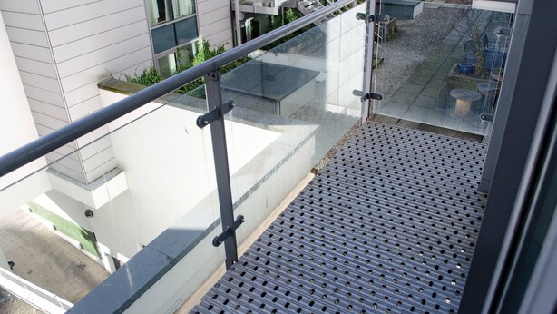 A modern building with a glass balcony, metal railings, and a patterned floor. - Henry Street - Apt 22 (Liverpool)