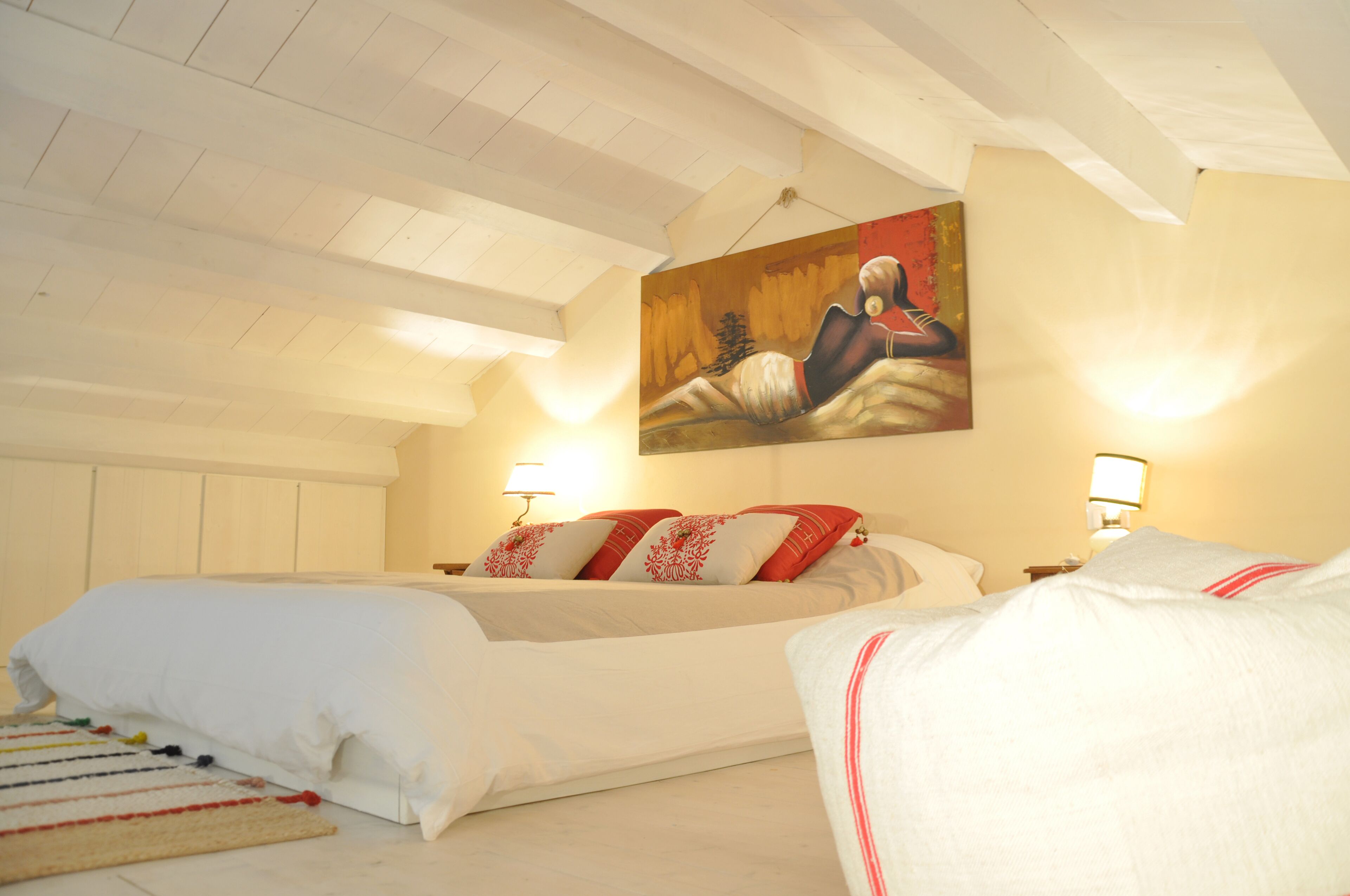 Een slaapkamer met een groot bed, twee nachtkastjes en een schilderij aan de muur.