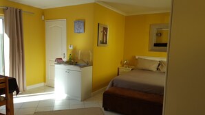 Une pièce comprenant un lit, un bureau avec un lavabo, une chaise et une fenêtre avec des rideaux.
