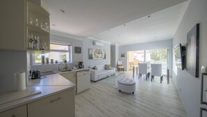 Eine moderne Küche mit Essbereich, einem weißen Sofa und einem Glastisch.