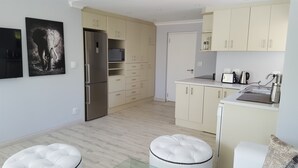 Eine moderne Küche mit hellen Holzschränken, einem Edelstahlkühlschrank und einer weißen Arbeitsplatte mit Wasserkocher und Toaster.