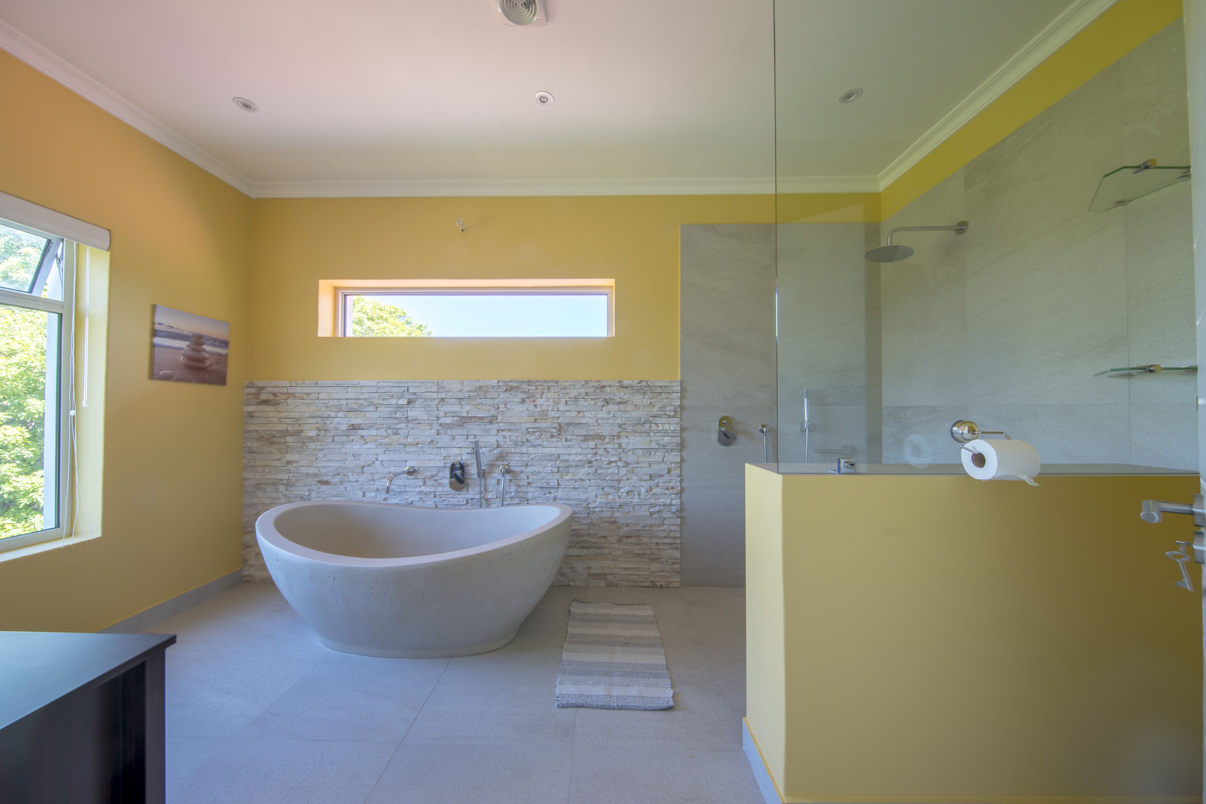 A modern bathroom with a freestanding bathtub, a glass shower enclosure, and a yellow vanity.