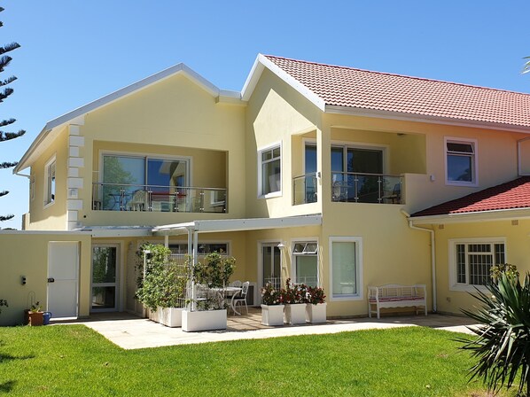 Ein zweistöckiges Haus mit Balkon, überdachter Terrasse und gepflegtem Rasen.