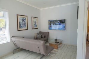 A modern living room with a sofa, a coffee table, and two framed artworks on the wall.