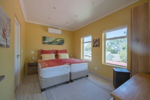 Ein Schlafzimmer mit zwei Betten, einem Fenster und Bildern an den Wänden.