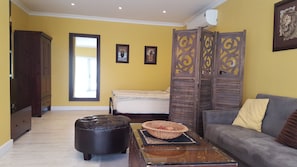 A room with a bed, a sofa, a wooden cabinet, and a decorative screen.