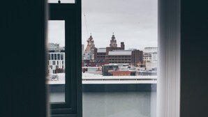 A room with a bed and a window overlooking a cityscape. - Kent Street - Apt 15 (Liverpool)