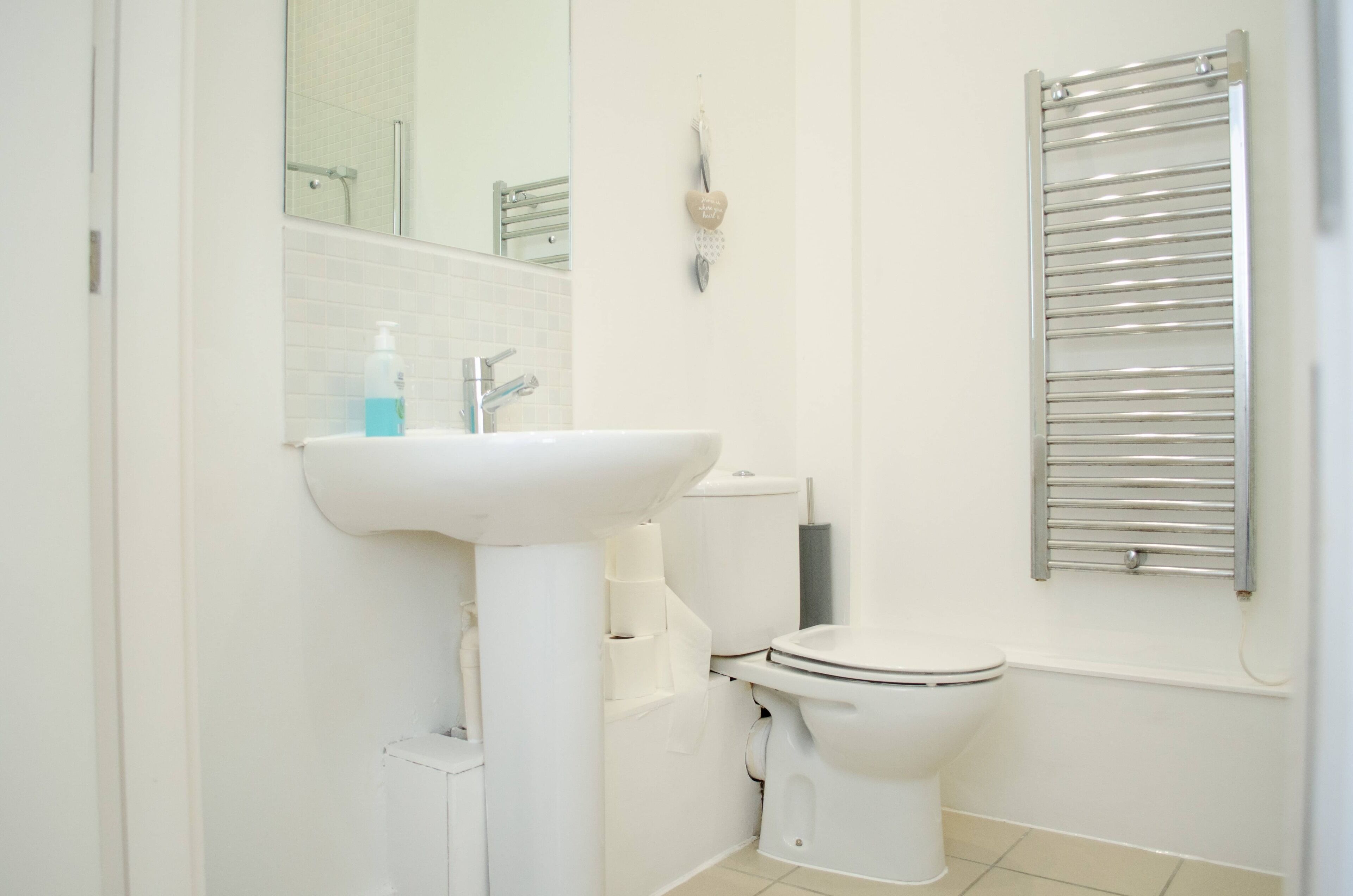A modern bathroom with a white sink, toilet, and a towel rack.