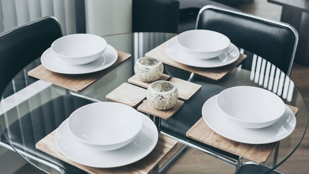A modern dining area with a glass table surrounded by chairs, white plates, and a decorative stone bowl. - Kent Street - Apt 17 (Liverpool)