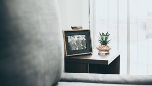 A framed photograph on a wooden table next to a window with a plant. - Kent Street - Apt 17 (Liverpool)