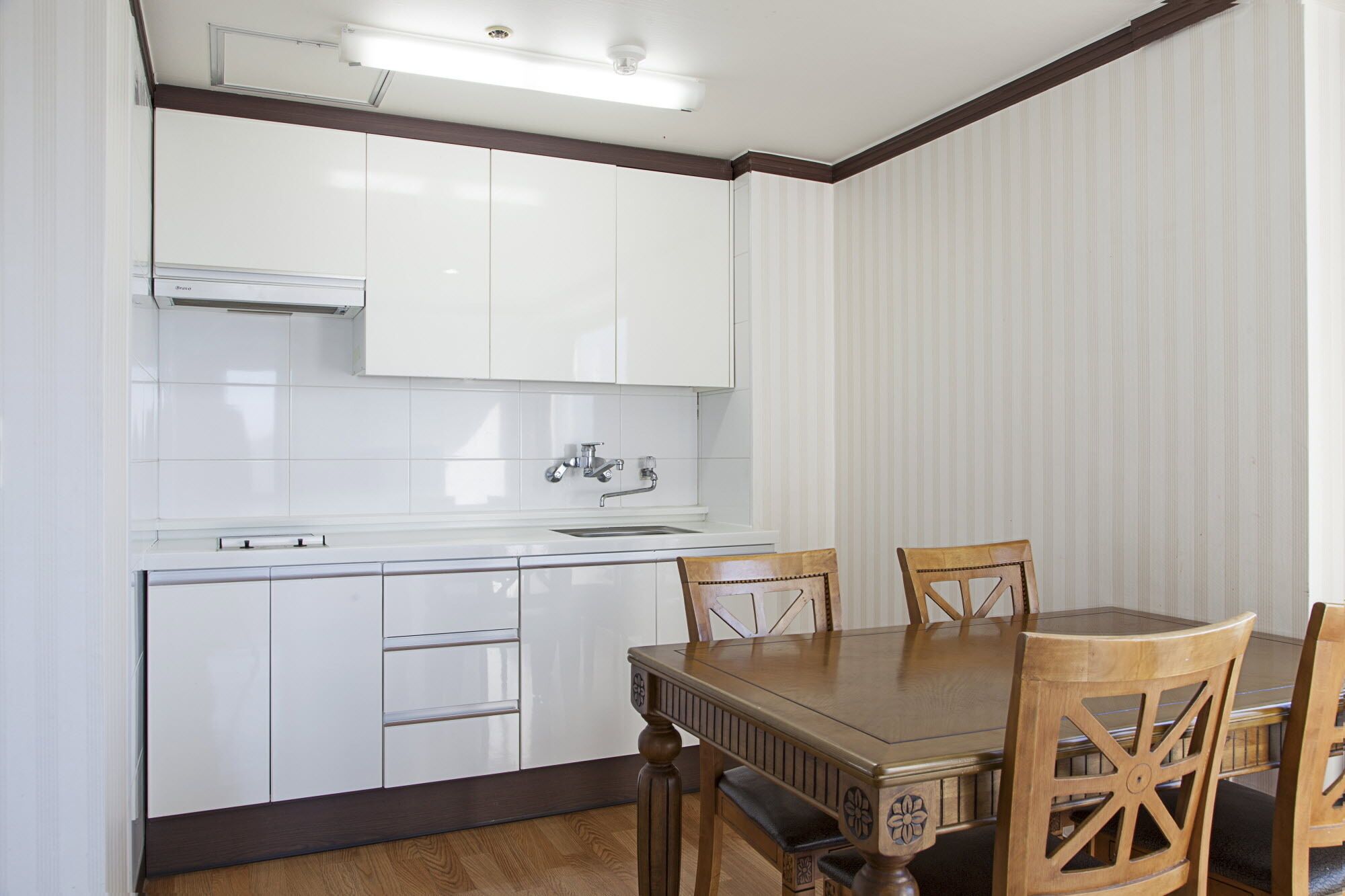 A kitchen with white cabinets, a sink, and a dining table with chairs.