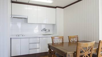A kitchen with white cabinets, a sink, and a dining table with chairs.