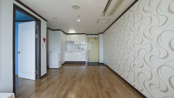 A hallway with wooden flooring, white walls, and a patterned wallpaper on one side.