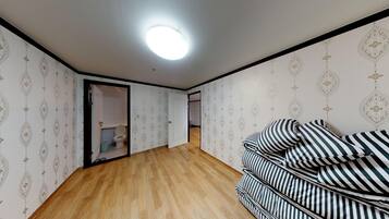 Une pièce avec un plancher en bois, un canapé à rayures et un papier peint à motifs.