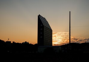 A tall building with a unique sloped roof, set against a sunset sky. - The Witt DOGO (Asan)