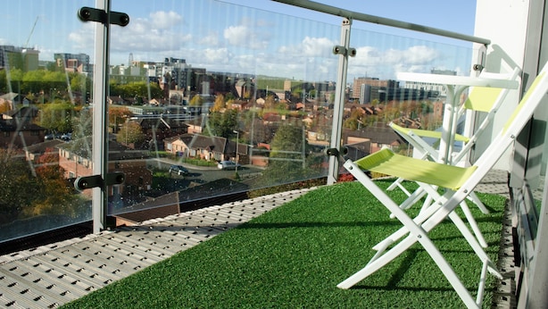 A balcony with a glass railing, a green artificial turf, and a white folding chair. - Kent Street - Apt 8 (Liverpool)