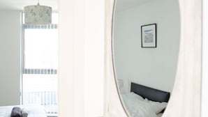 A bedroom with a bed, a large mirror, and a window. - Kent Street - Apt 8 (Liverpool)