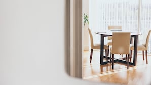 A dining area with a round table and four chairs, a potted plant, and a large window with blinds. - Kent Street - Apt 8 (Liverpool)