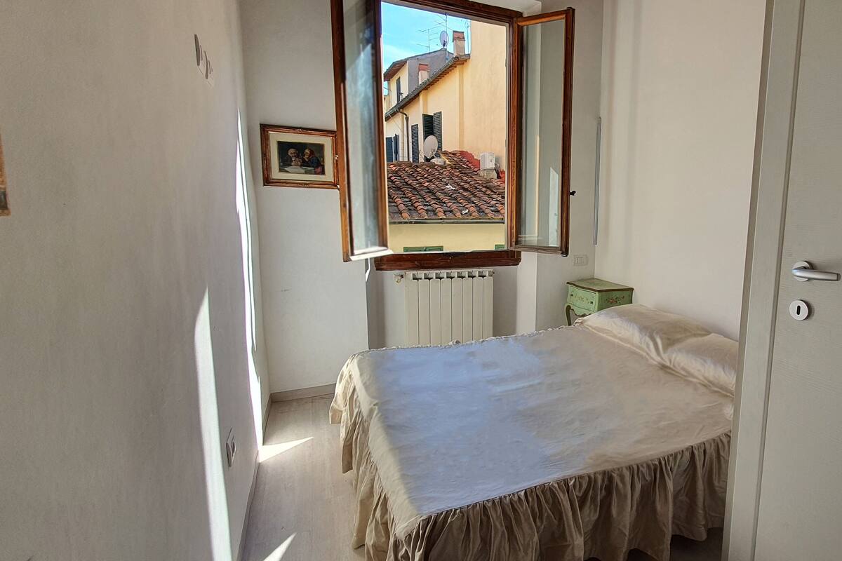 A narrow room with a bed, a radiator, and a small bedside table.