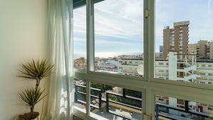 Une fenêtre donnant sur un quartier résidentiel, avec vue sur des immeubles et un ciel dégagé.