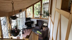 Een gezellige kamer met een open haard, comfortabele zitmogelijkheden en grote ramen met uitzicht op de natuur.