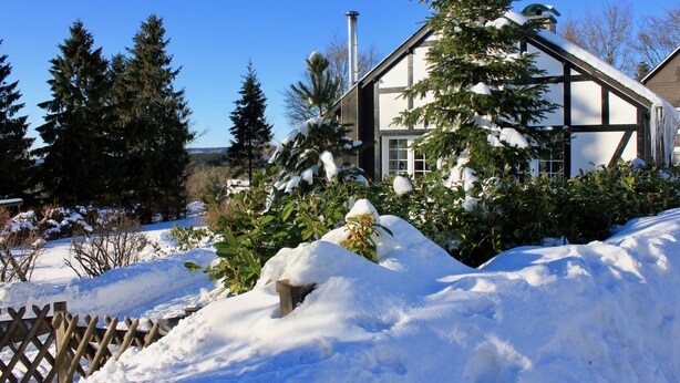 Een huis met een sneeuwbedekte kap en schoorsteen.