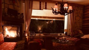Een gezellige kamer met een open haard, een stenen muur, een houten bank en een glazen tafel met een lamp.